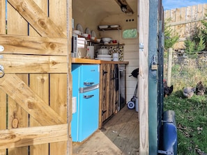 Una cocina pequeña con un refrigerador azul, armarios de madera y un ventanal.