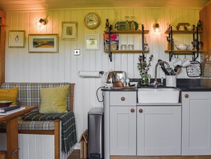 A kitchen with white cabinets, a wooden countertop, a clock, and various kitchen items.