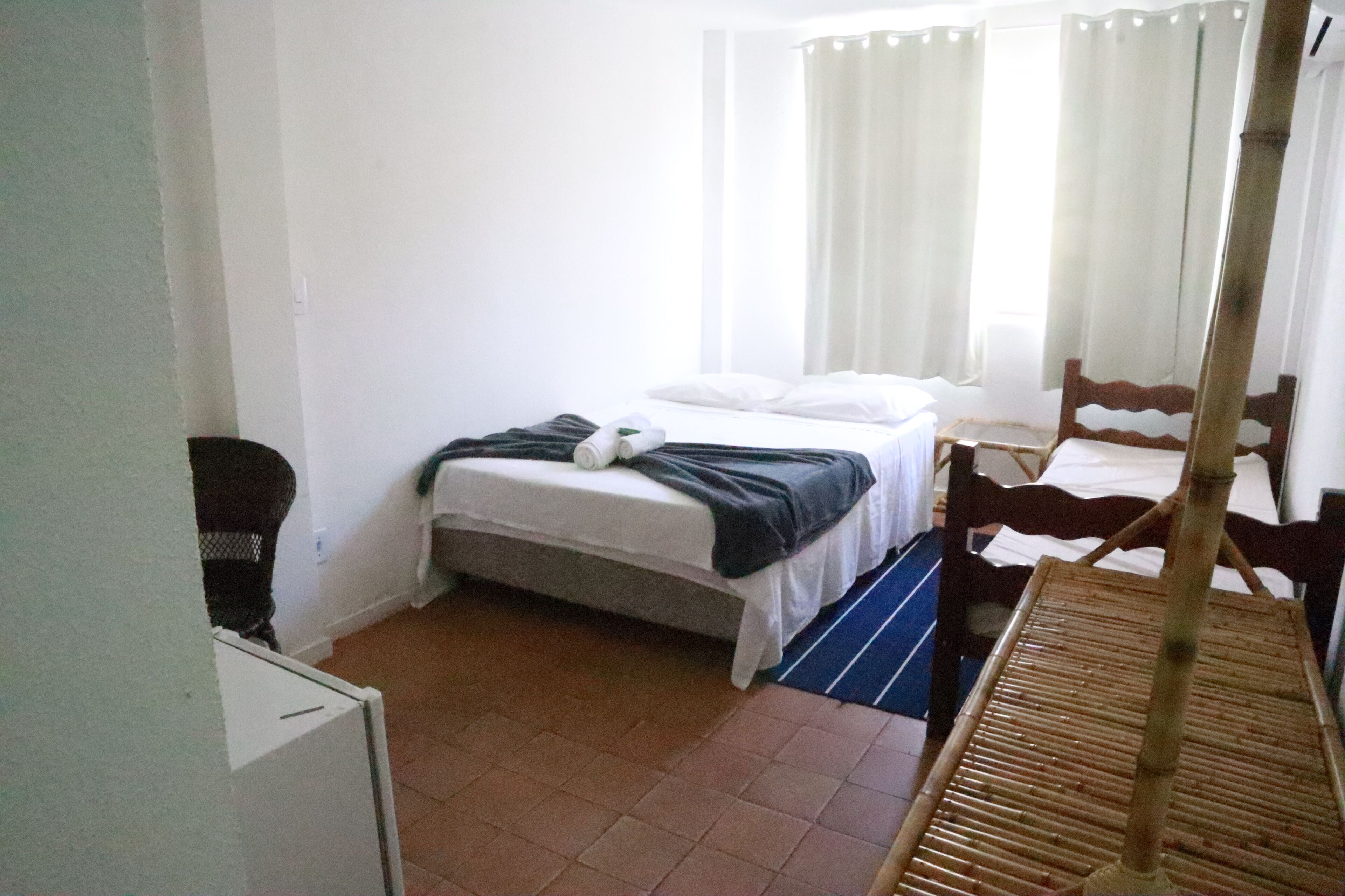 A small, simple room with a bed, a chair, and a table.