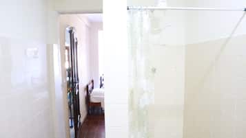 Ein Badezimmer mit weiß gefliesten Wänden, einer Duschvorhang und einer sichtbaren Toilette.