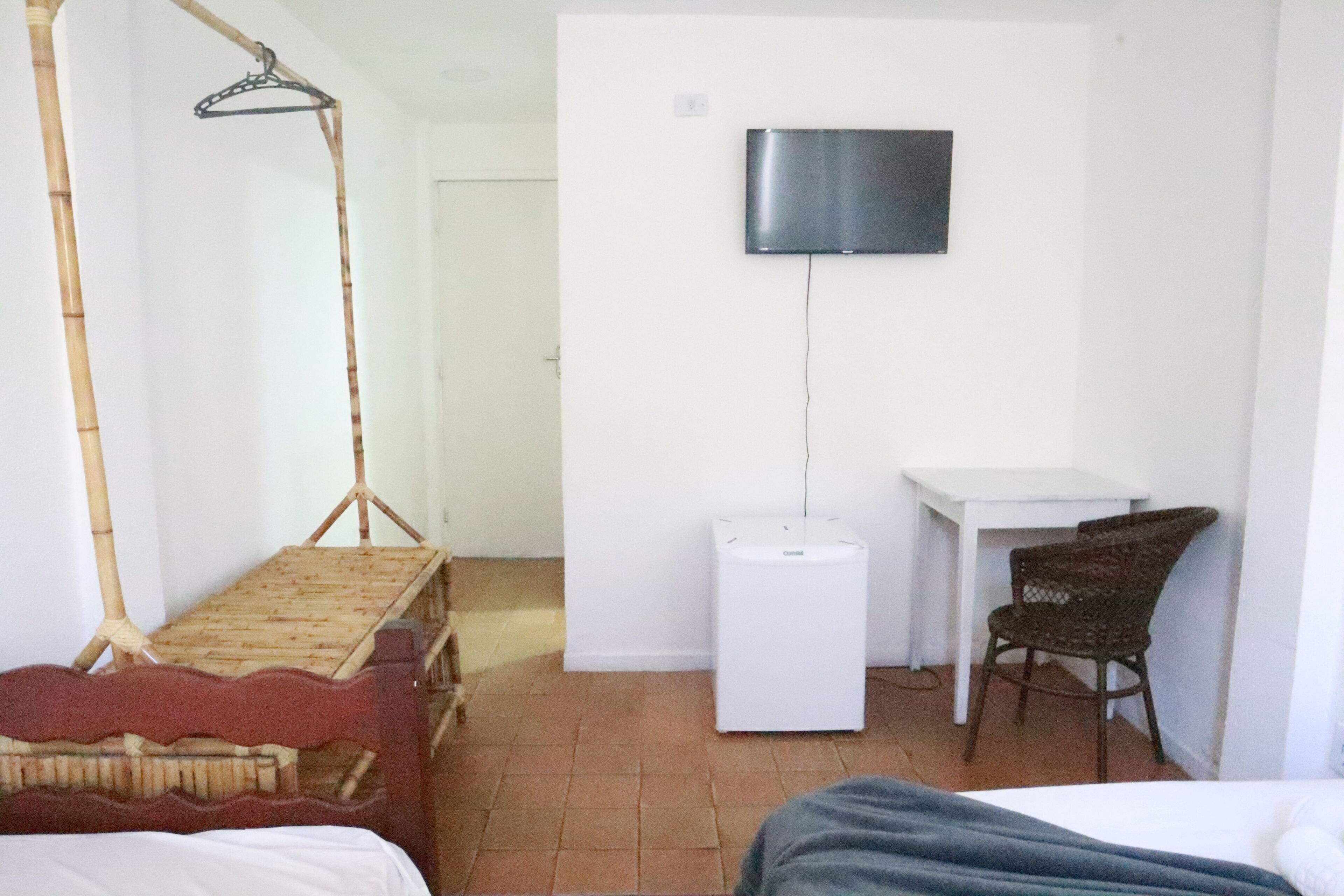 A room with a bed, a desk, a chair, a television, and a small white cabinet.