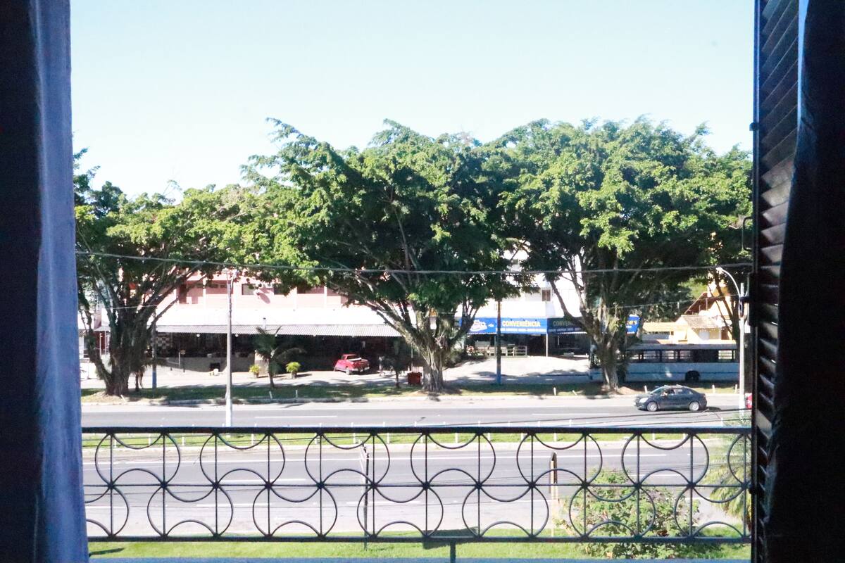A view of a street with trees, a red car, and a blue building with a sign that reads "CONVENIENTIA".