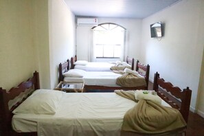 A room with three single beds, a small table, and a window with curtains. - Pousada Lisamar (Mangaratiba)