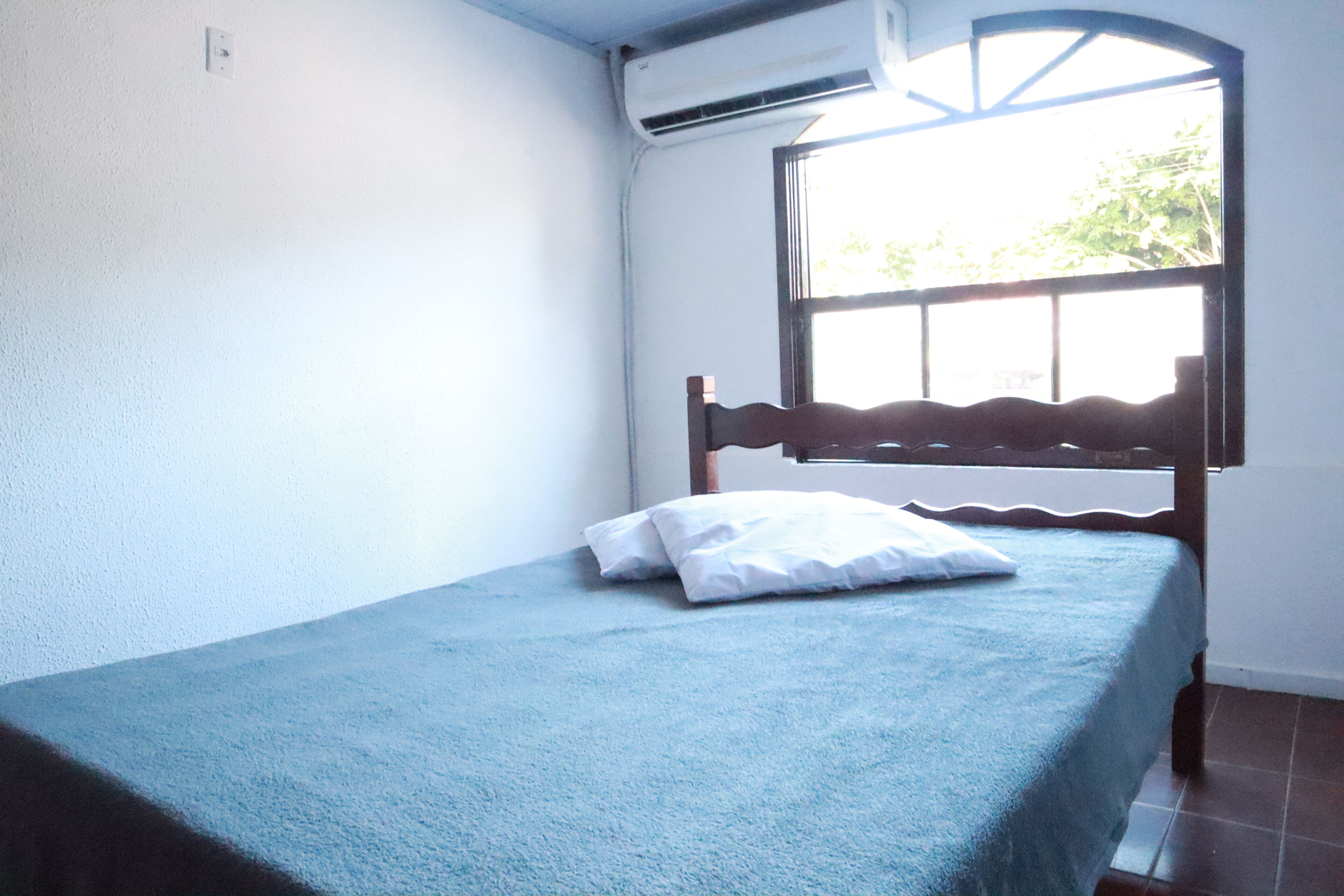 A single bed with a wooden headboard and a blue bedspread.