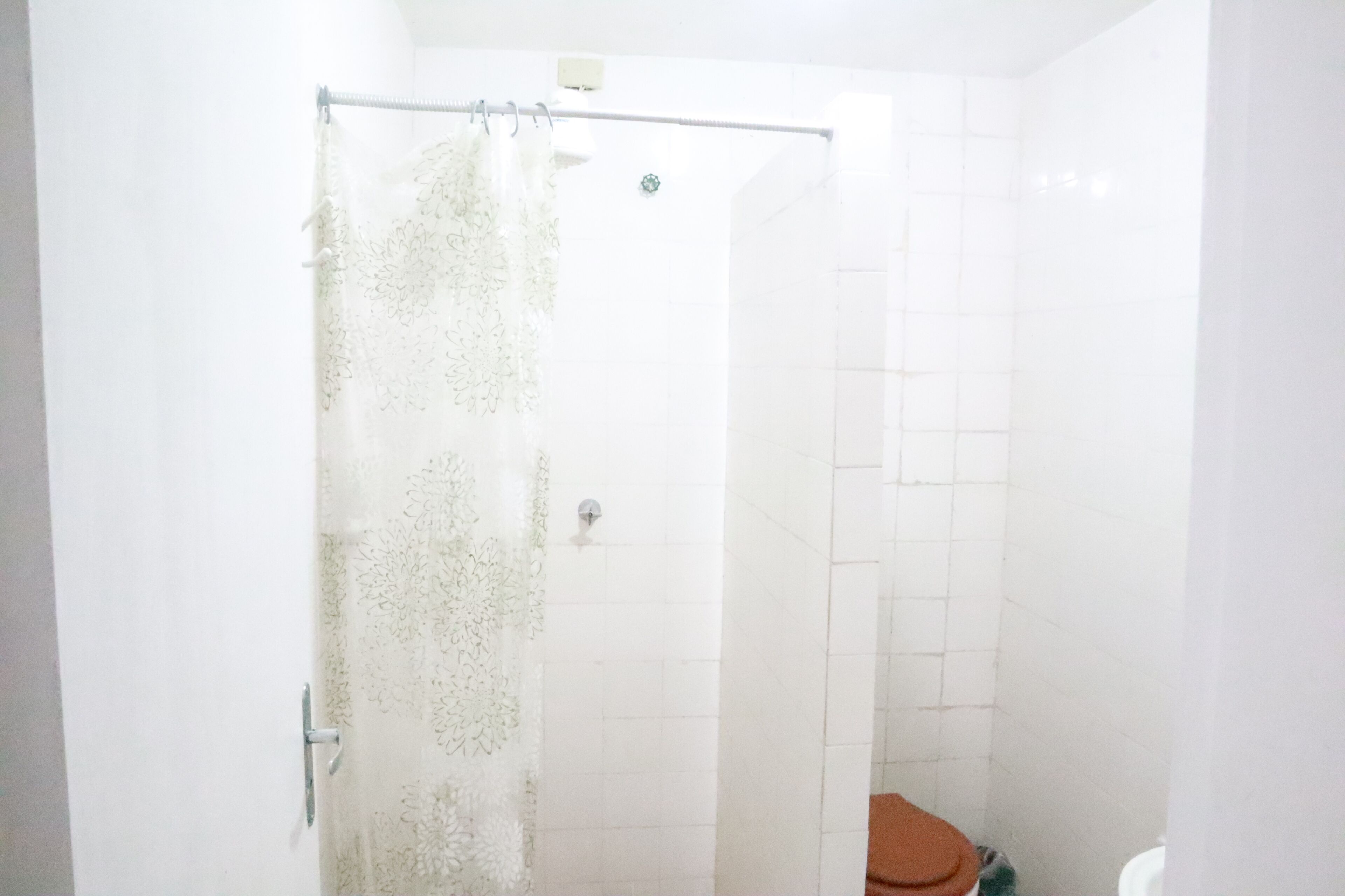 A bathroom with a shower curtain, a toilet, and tiled walls.