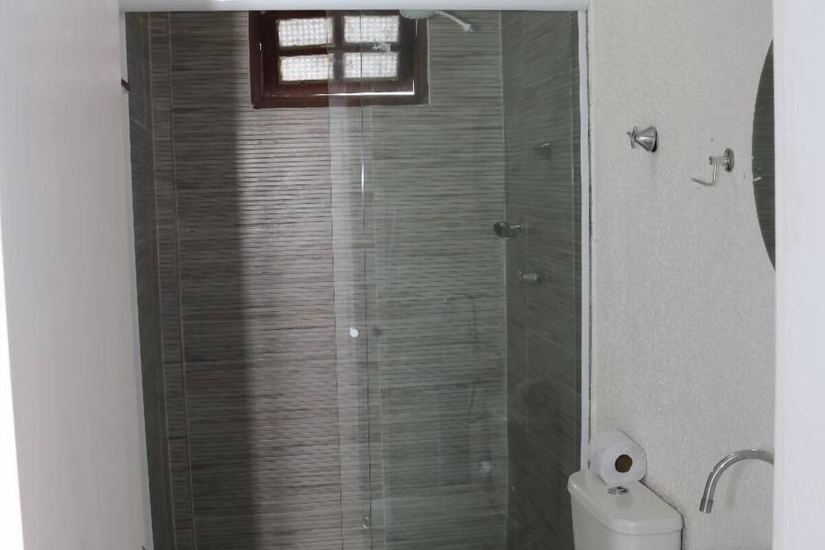 A bathroom with a glass-enclosed shower, a toilet, and a sink.