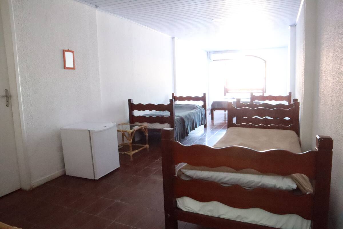 A room with two wooden beds, a small white refrigerator, and a chair.
