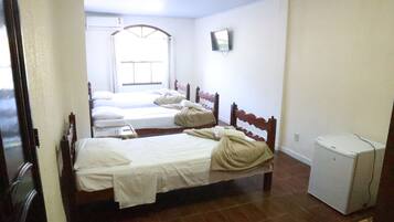 Quarto de hotel com duas camas, um pequeno frigorífico e janela com vista.