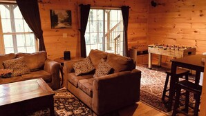 A cozy cabin interior with a sofa set, a foosball table, and a dining table.