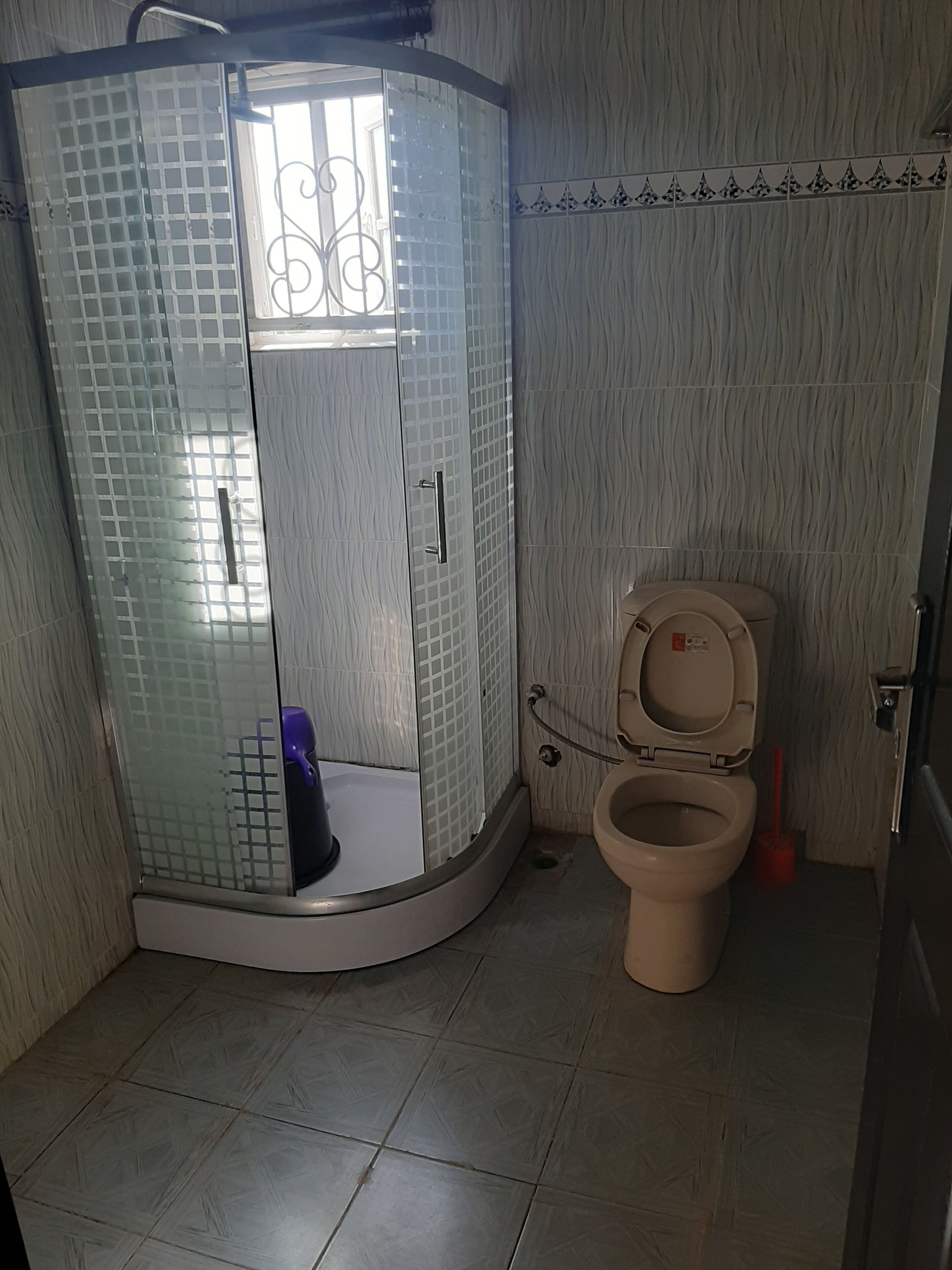 Un bany amb dutxa de vidre, vàter i rentatge.
