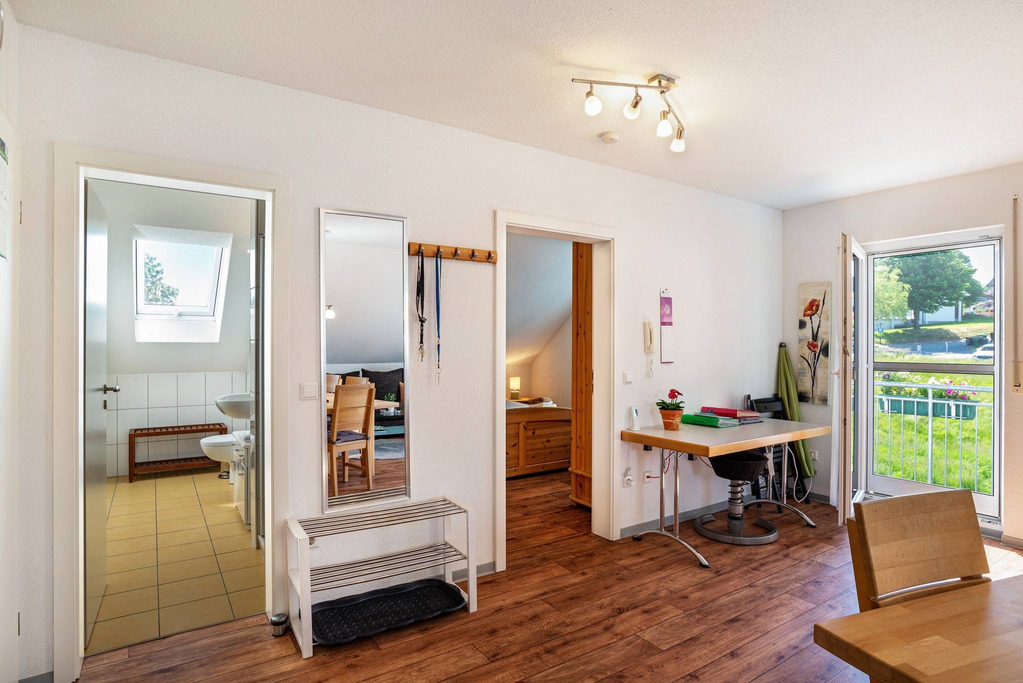 Een modern interieur met een houten vloer, een eethoek, een keuken en een badkamer.