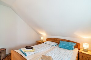 A bedroom with a wooden bed, two bedside tables, and a nightstand.