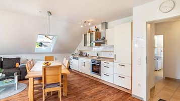 Een modern appartement met een eethoek, keuken en een slaapkamer op een entresol met dakraam.