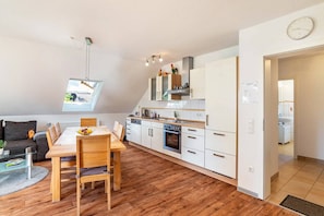 Un apartamento moderno con comedor, cocina y habitación doble tipo loft con tragaluz.