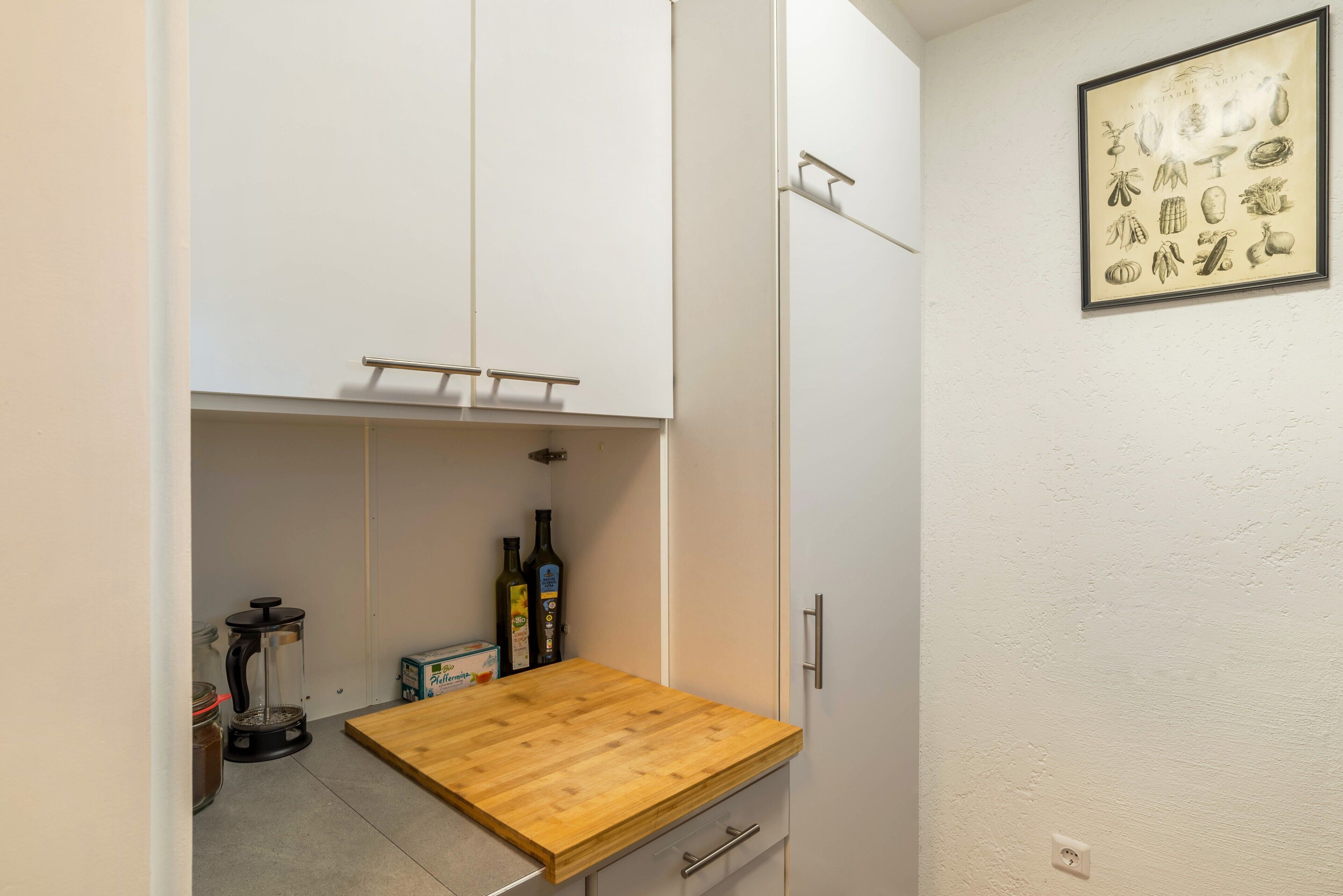 Eine kleine Küche mit Holzarbeitsplatte, einer Kaffeemühle und einem Schrank.
