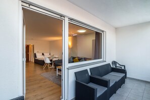 An open sliding door leading to a living area with a sofa, chairs, and a dining table.