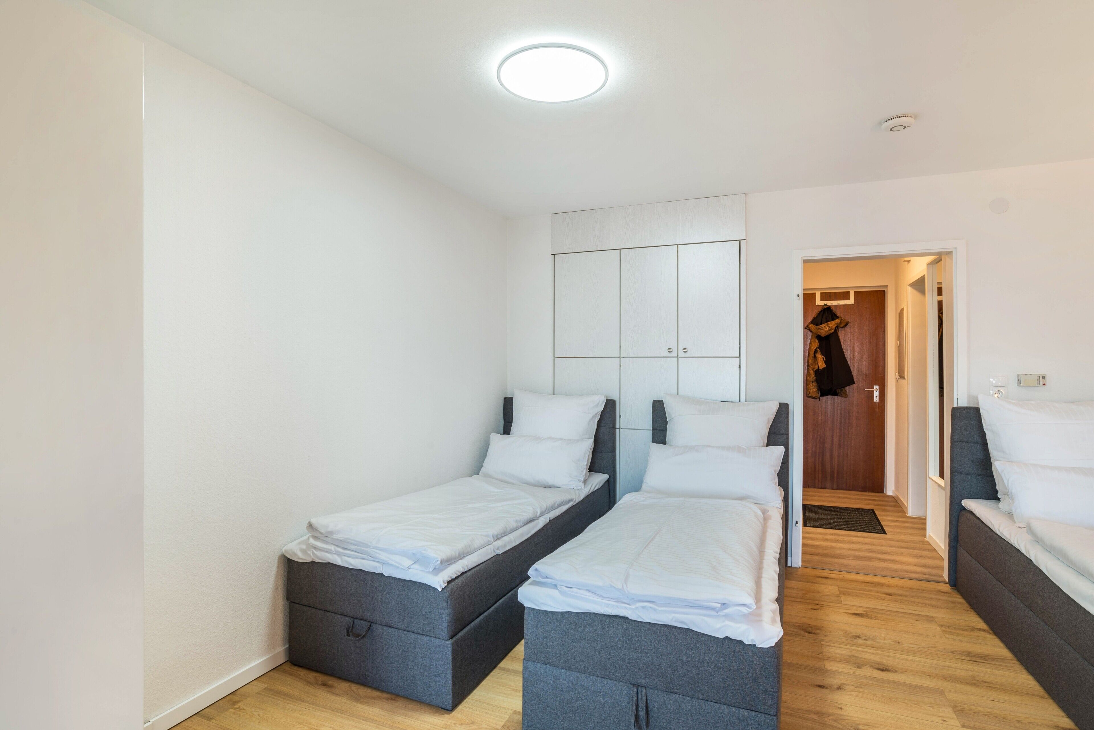 Ein Schlafzimmer mit zwei Einzelbetten, einem Kleiderschrank und einer Tür zu einem anderen Raum.