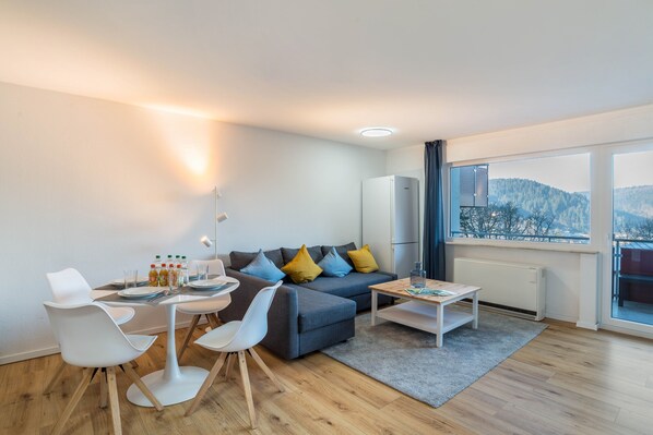 A modern living room with a sofa, chairs, a coffee table, and a dining area.