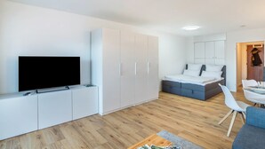 Un espace de vie moderne et compact, doté d’un téléviseur à écran plat, d’un lit, d’un coin repas et d’une kitchenette.