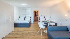 Une chambre moderne et compacte, comprenant un lit, un canapé, une table à manger et une armoire.