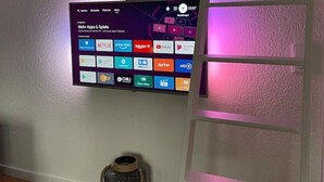 Et vægmonteret fladskærms-tv, der viser forskellige streaming-apps.