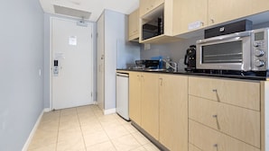 A compact kitchen with wooden cabinets, a built-in microwave, and a coffee maker.