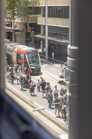 Un tramway avec des passagers, un passage piéton et un bâtiment avec une enseigne.
