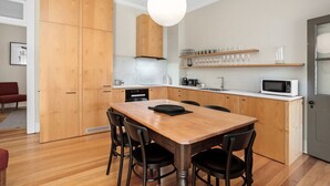 A modern kitchen with wooden cabinets, a marble countertop, and a dining area with a wooden table and chairs. - Stylish heritage home The Rocks (The Rocks)