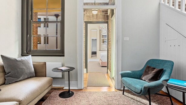 A cozy living room with a sofa, a chair, a small table, and a view through an open door to a bedroom. - Stylish heritage home The Rocks (The Rocks)