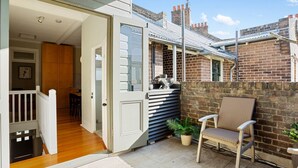 An open door leading to a room with a wooden floor, a chair, and a potted plant. - Stylish heritage home The Rocks (The Rocks)