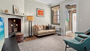 A living room with a sofa, a lamp, a fireplace, and a view through a window. - Stylish heritage home The Rocks (The Rocks)