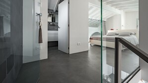 Una habitación de hotel moderna con separador de vidrio, una cama, un baño y una zona de cocina.