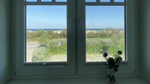 Una habitación con dos ventanas que dan a un paisaje costero.