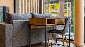 A modern room with a grey sofa, a wooden desk, and a black chair. - Condesa Cholula Lofts by VH (Mexico City)