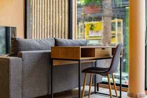 Una habitación moderna con un sofá gris, un escritorio de madera y una silla negra.