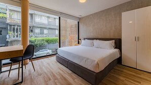 A modern bedroom with a large bed, a desk, and a chair. - Condesa Cholula Lofts by VH (Mexico City)