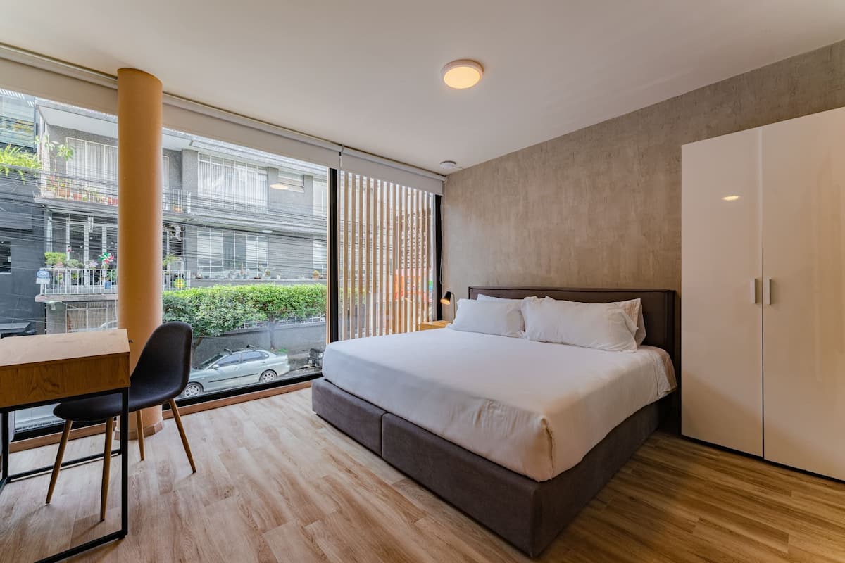 A modern bedroom with a large bed, a desk, and a chair.