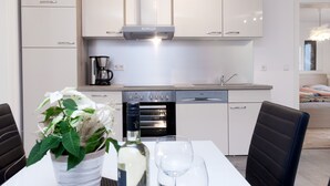 A modern kitchen with a built-in oven, coffee maker, and a dining area with a table set for two. - Moderne Ferienwohnung in Öhringen mit Idealer Anbindung zur Autobahn (Öhringen)