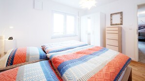 A bedroom with two beds, a dresser, a mirror, and a window. - Moderne Ferienwohnung in Öhringen mit Idealer Anbindung zur Autobahn (Öhringen)
