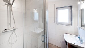 A modern bathroom with a glass-enclosed shower, a white sink, and a window. - Moderne Ferienwohnung in Öhringen mit Idealer Anbindung zur Autobahn (Öhringen)