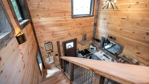 L’intérieur d’une cabane en bois comprend un coin cuisine, un escalier et une fenêtre agrémentée d’un luminaire en forme d’étoile.