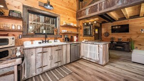 Une cuisine rustique avec des meubles en bois, un four à micro-ondes encastré et un évier.