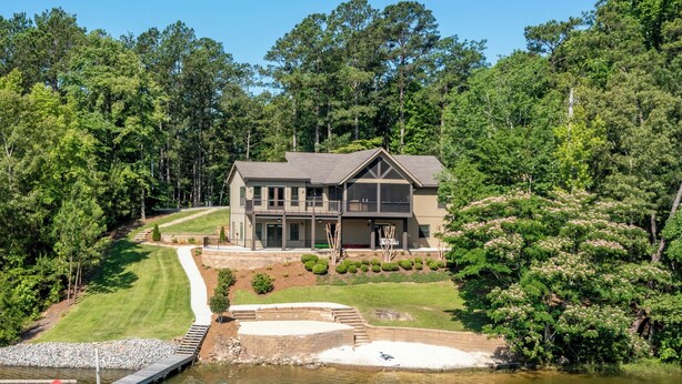 Une grande maison avec un quai s’avançant dans un lac, entourée d’une végétation luxuriante.