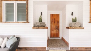 A hallway with white walls, a wooden door, and two shelves with cacti.