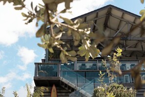 A modern building with a glass facade, a wooden deck, and a staircase leading to an upper level. - Beach Shack on Main Beach (Yamba)