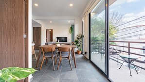 A modern dining area with a wooden table and chairs, a flat-screen TV, and a balcony with outdoor seating. - Doctores Apartments by VH (Mexico City)