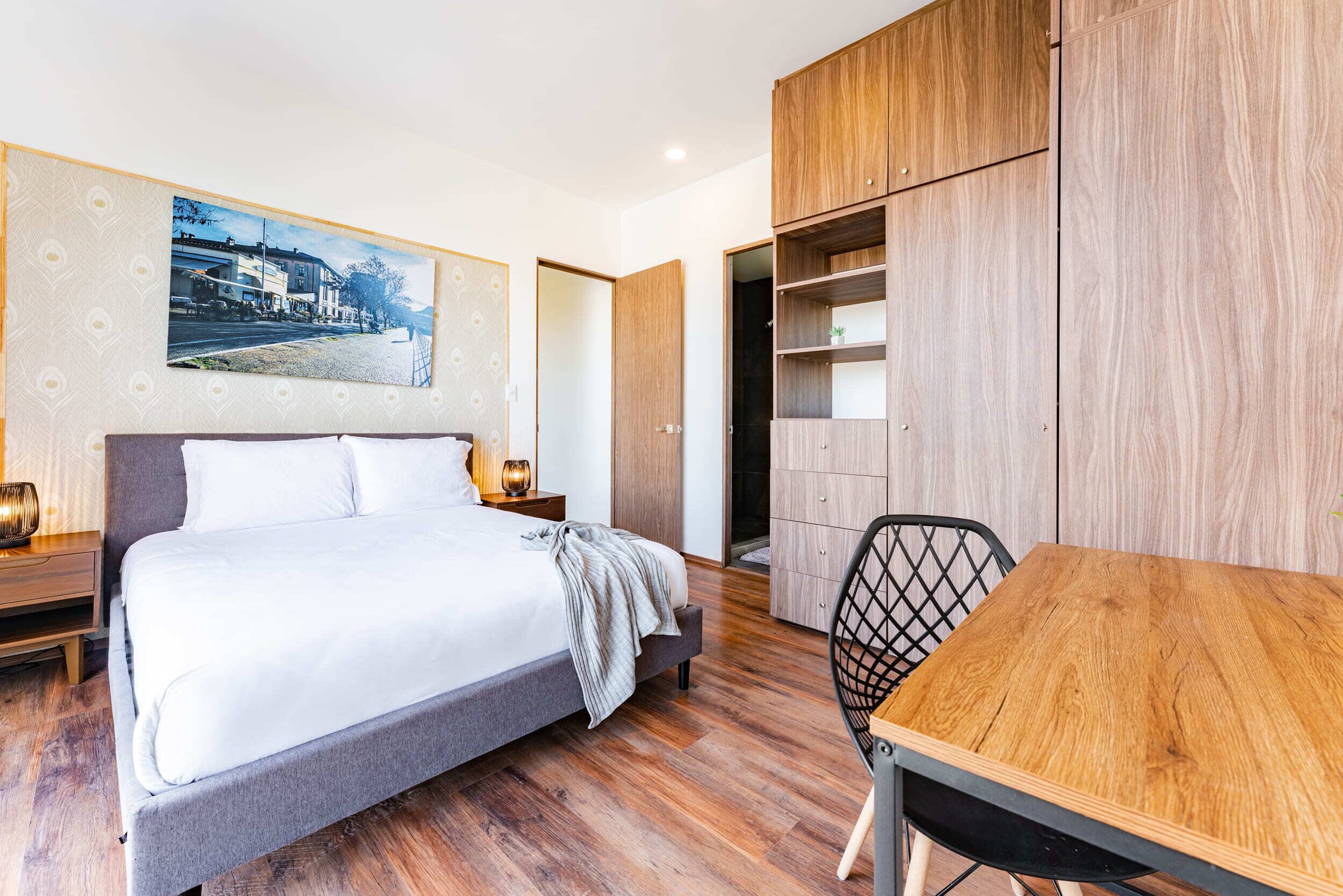 Une chambre moderne avec un grand lit, une armoire en bois et une table à manger.