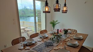Een eettafel voor zes personen met uitzicht op een meer door grote ramen.