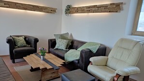 Een moderne woonkamer met leren banken, een houten salontafel en een rond poef.