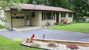 Une maison de plain-pied avec un garage, un porche à l’avant et une pelouse bien entretenue.